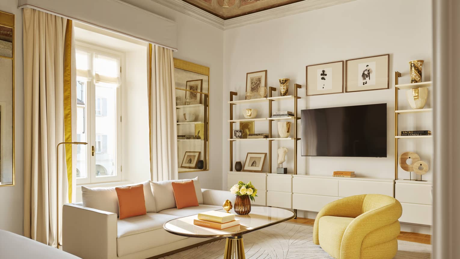 Modern luxury hotel suite with frescoed ceiling and sitting room with yellow arm chairs and white sofa