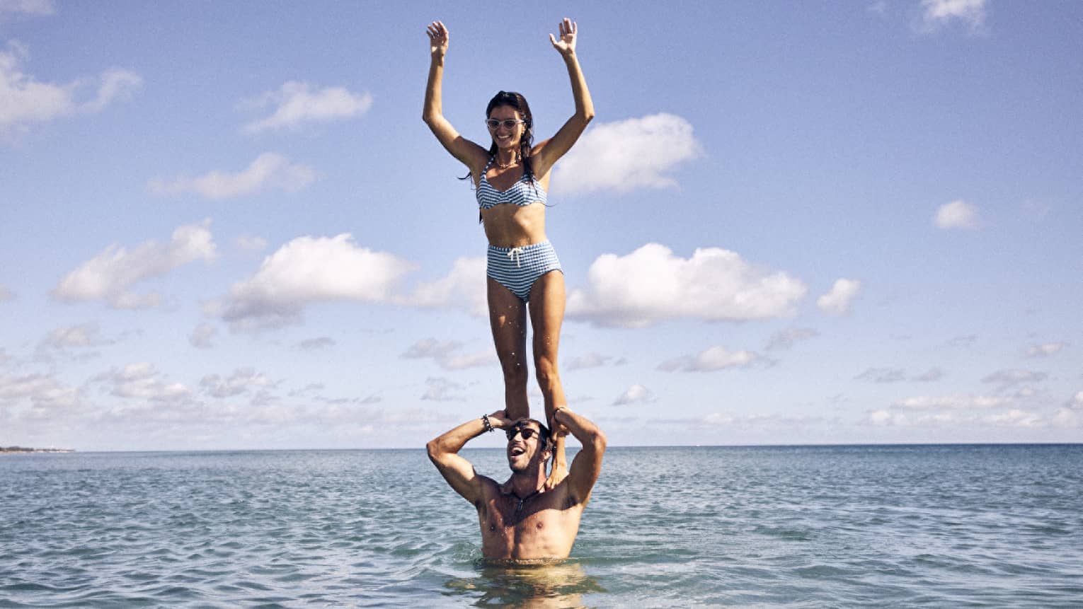 One guest standing on another guest's shoulders in the ocean.