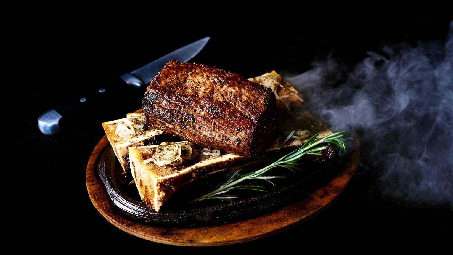 Chateaubriand Big Island roasted bone marrow on plate, rosemary, knife