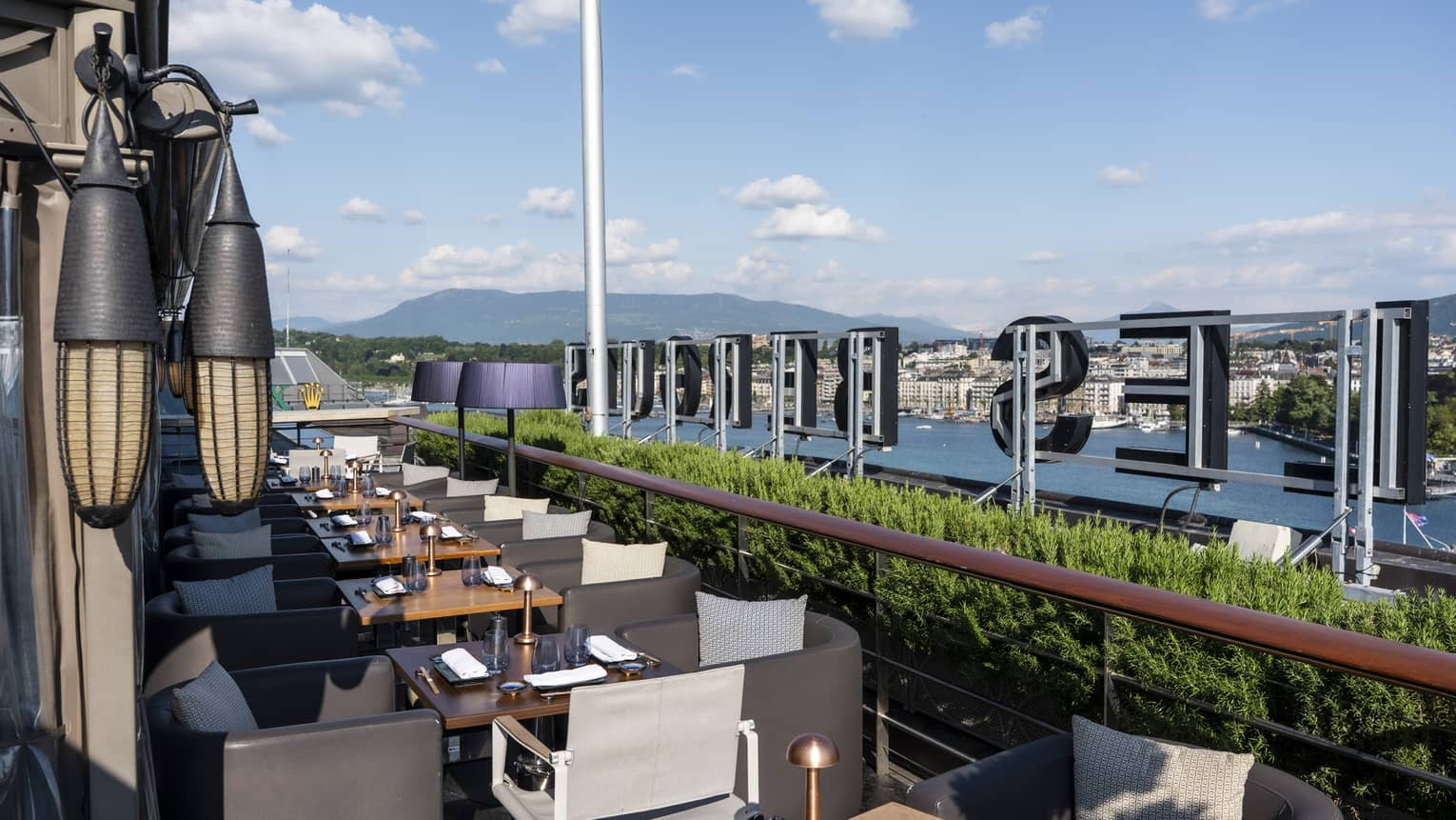 An outdoor dining space on a terrace with city views and mountains in the background