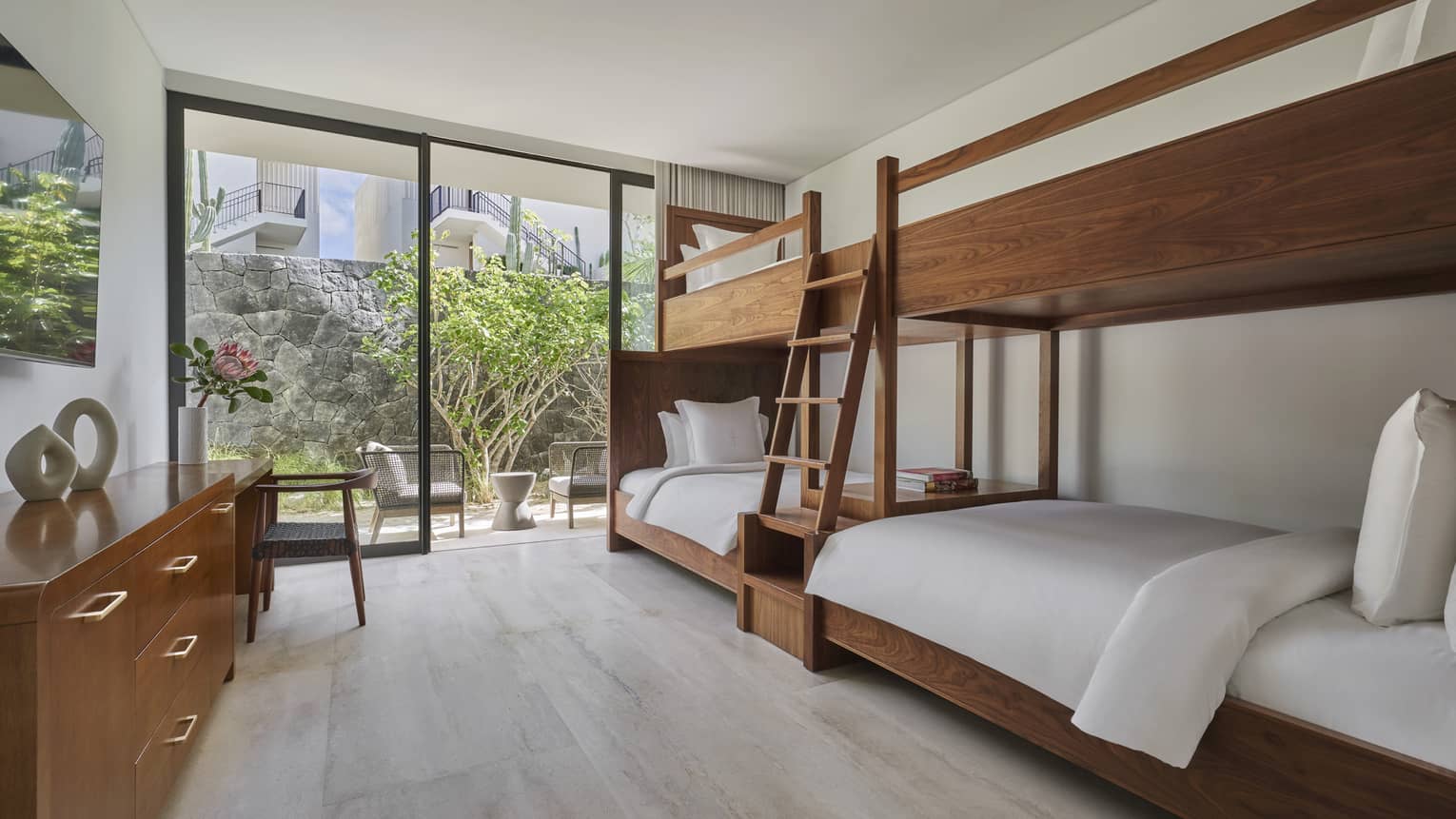 Bedroom with two wooden bunk beds connected together by ladder, walk-out patio