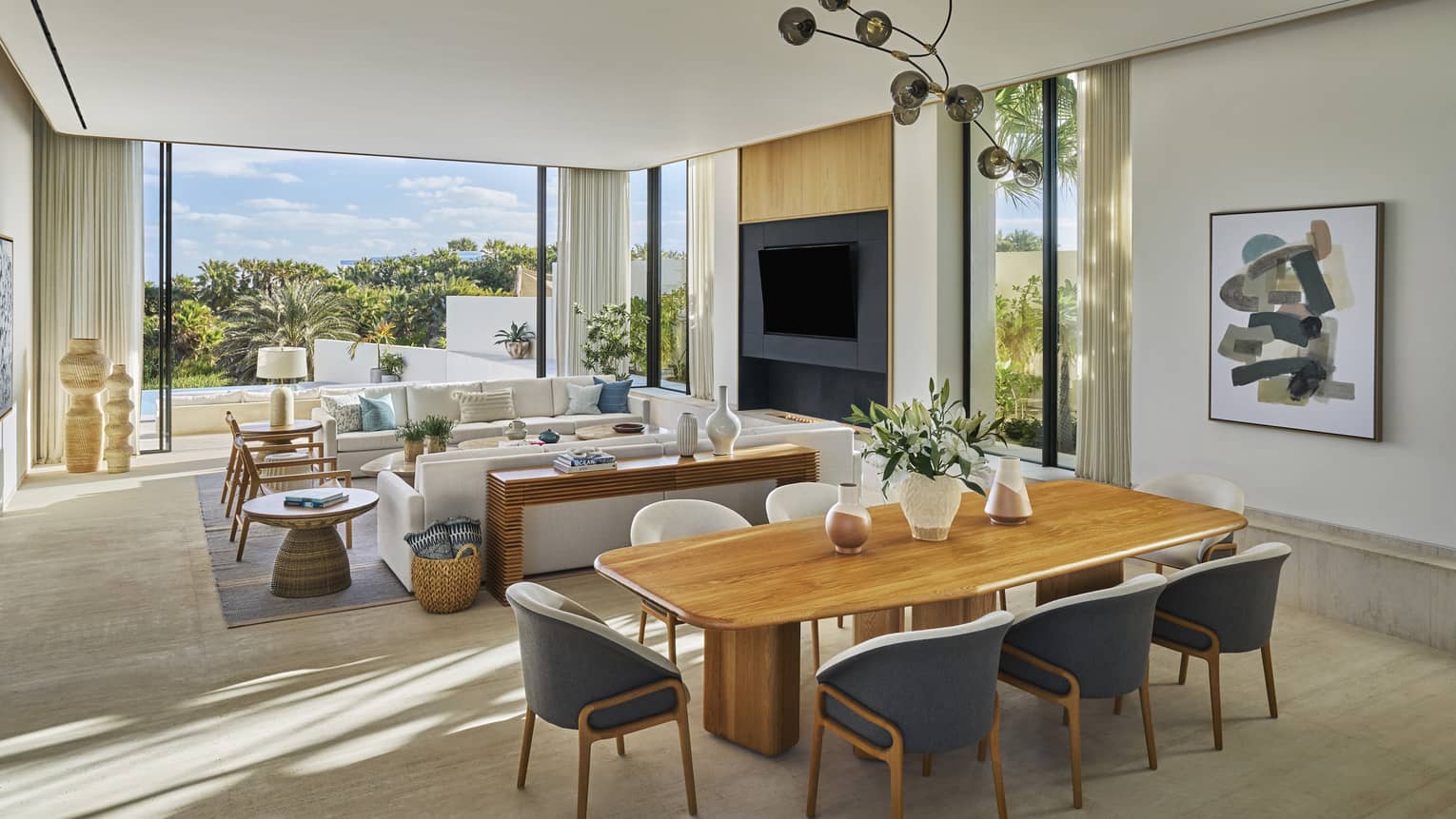Dining table with eight seats and adjacent living room and walk-out pool terrace of a private villa at Four Seasons Resort and Residences Los Cabos