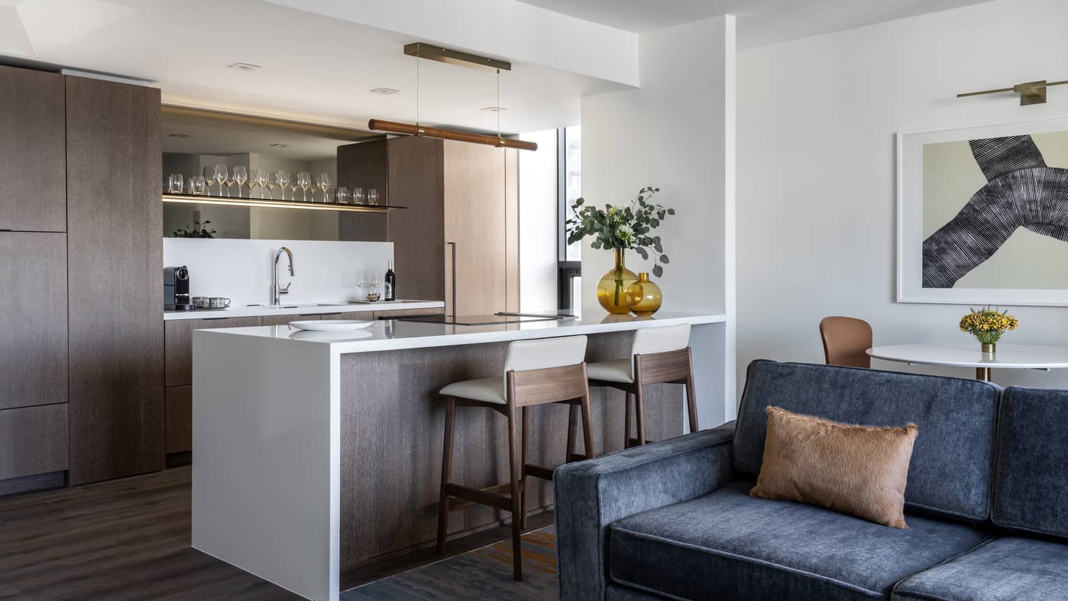 Kitchen area with white island, two chairs, wooden cabinets