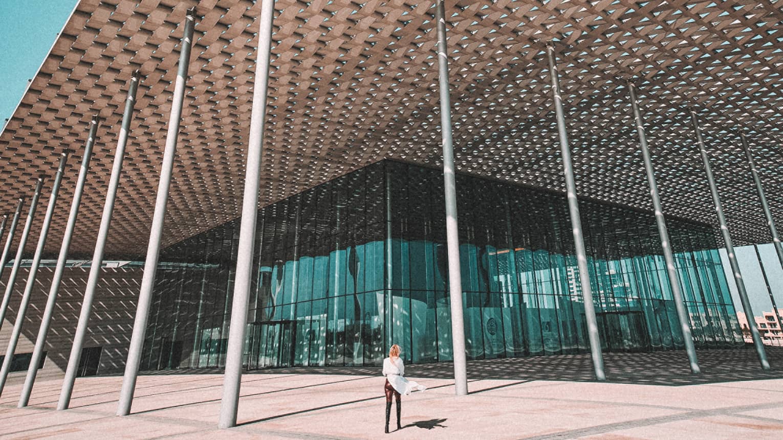 A building with a metal thatching on the roof, held up by a series of pillars.