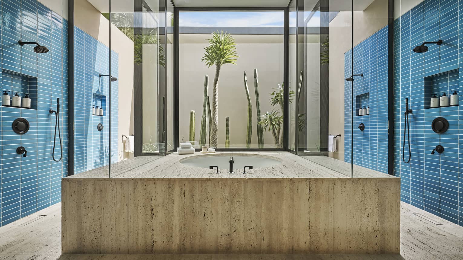 Large contemporary bathroom with two blue tile walls, each with a shower, and a large modern bathtub in the middle, at Four Seasons Resort and Residences Los Cabos