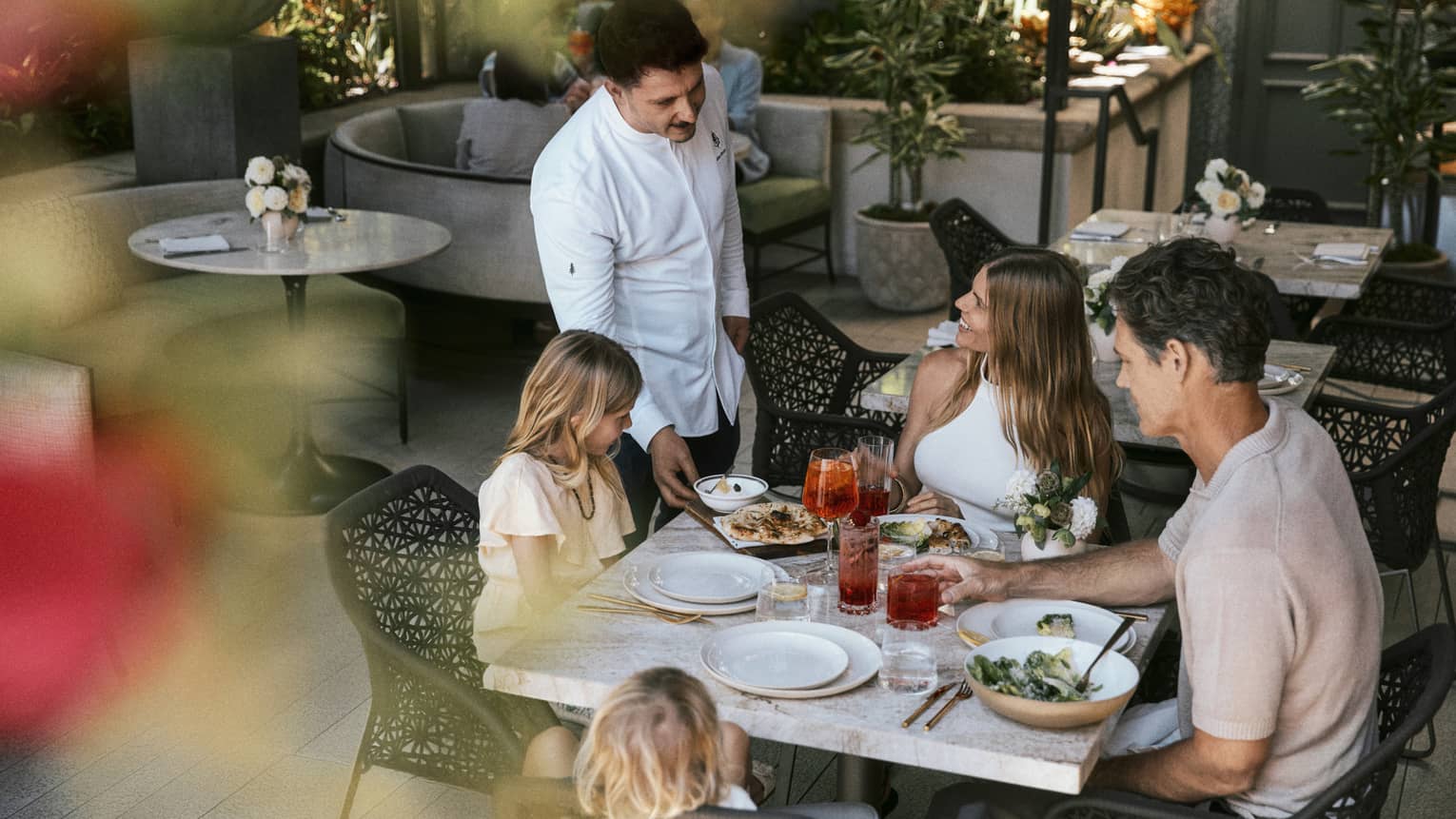 Family of four dines at a table on a restaurant terrace