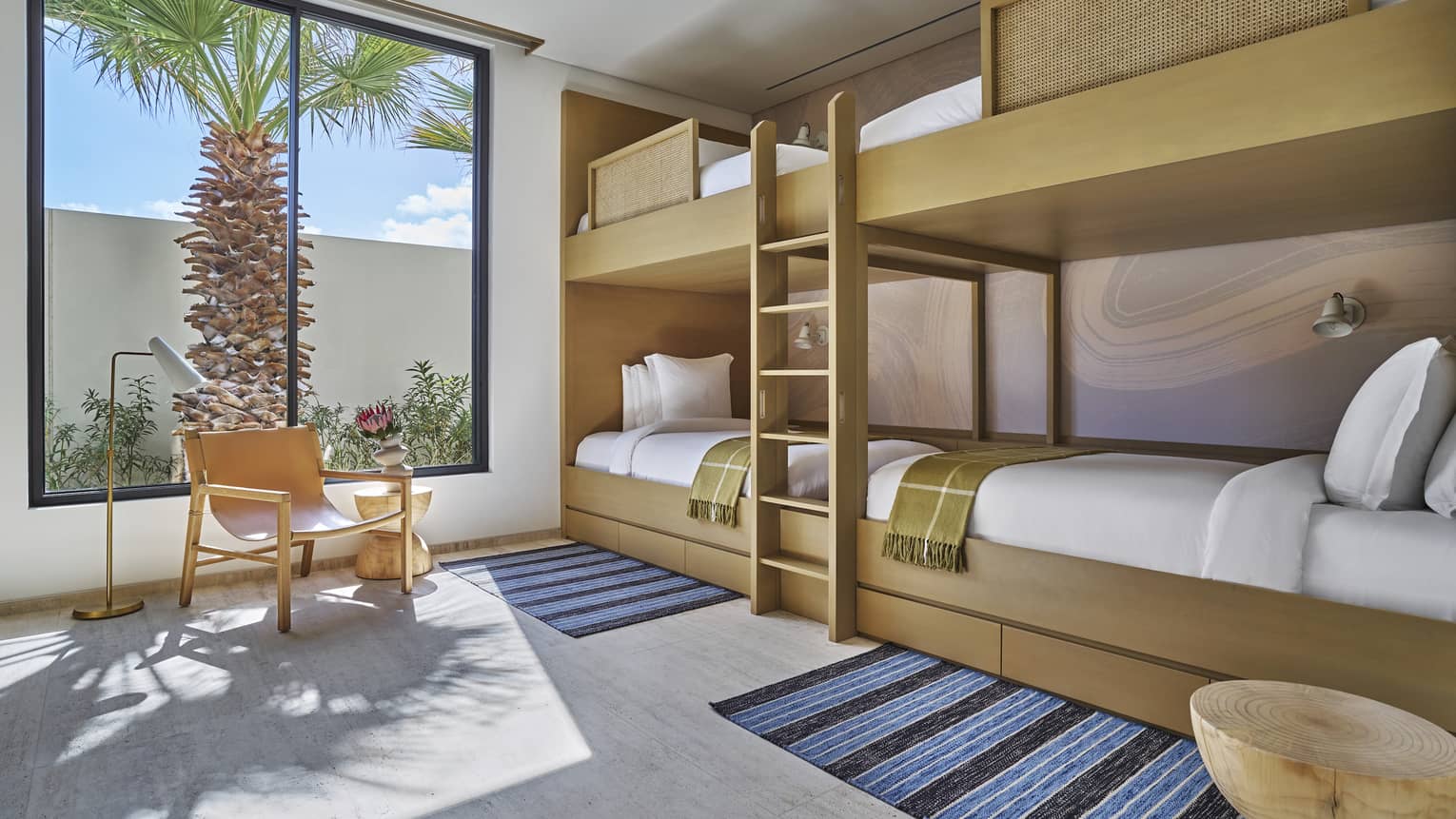 Kids room with a wall of bunk beds (four beds total) and a window with palm tree view at Four Seasons Resort and Residences Los Cabos