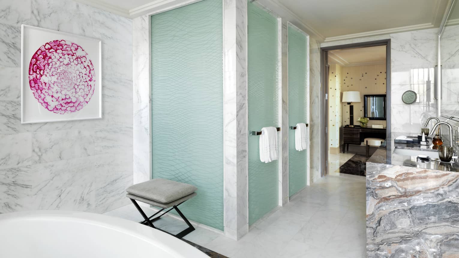 Two glass showers with white towels on handles in white marble bathroom near large vanity, pink painting