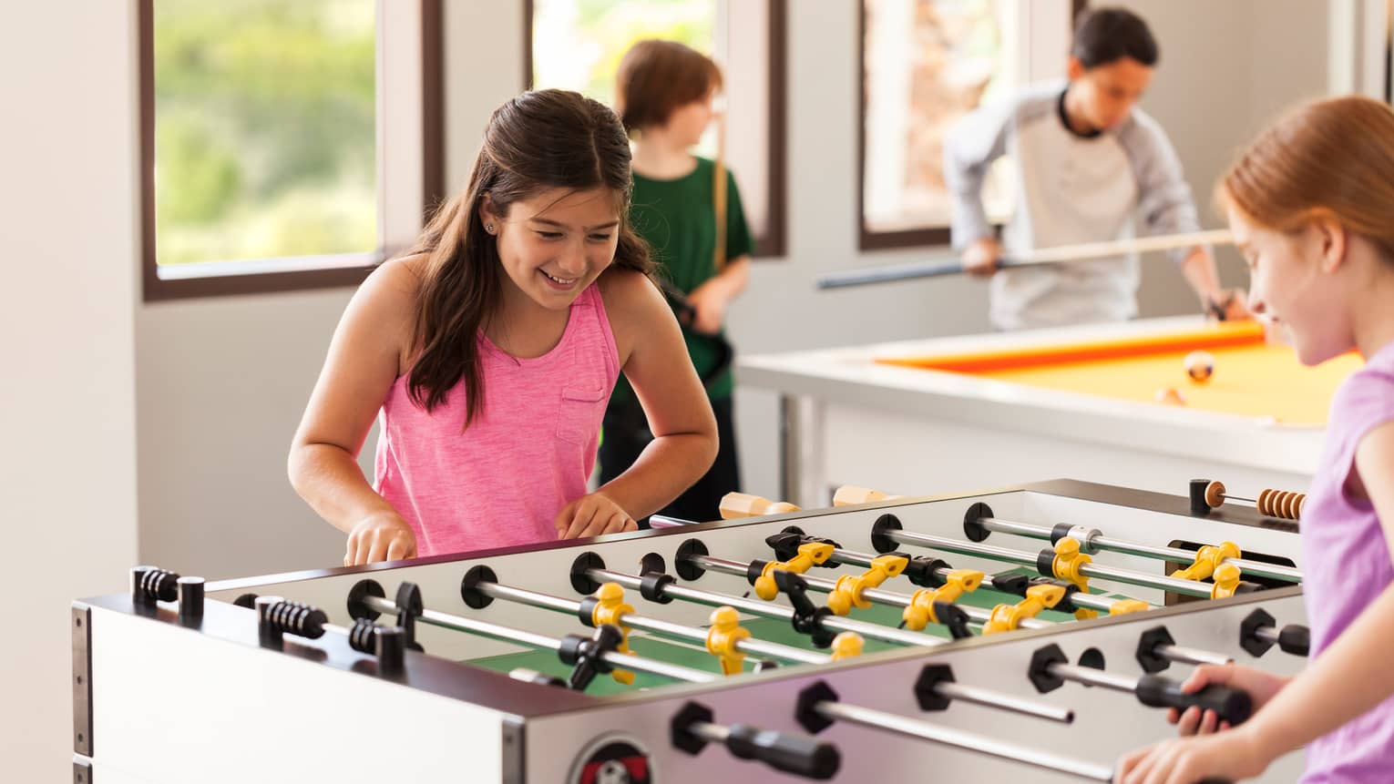 Young teens play table soccer in sunny Teen Centre activity room
