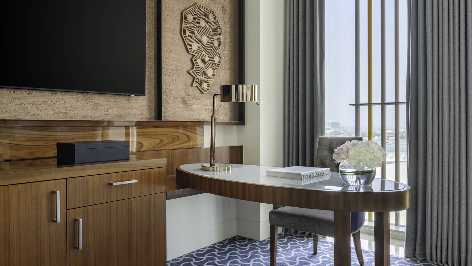 Hotel room with desk and dresser by floor-to-ceiling window