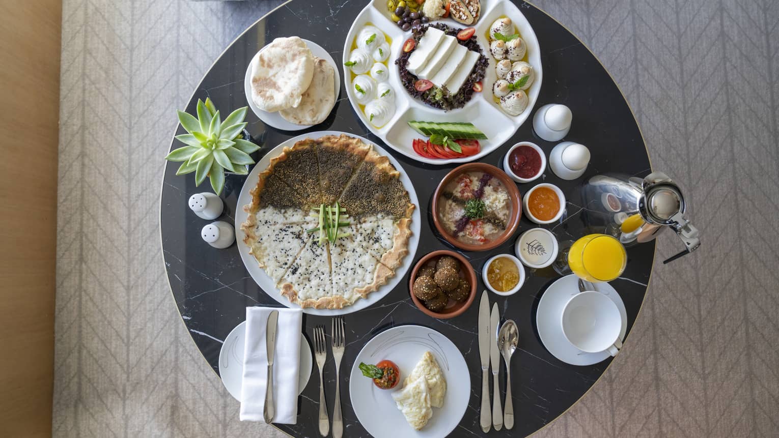 A variety of breakfast dishes presented on a round black marble table