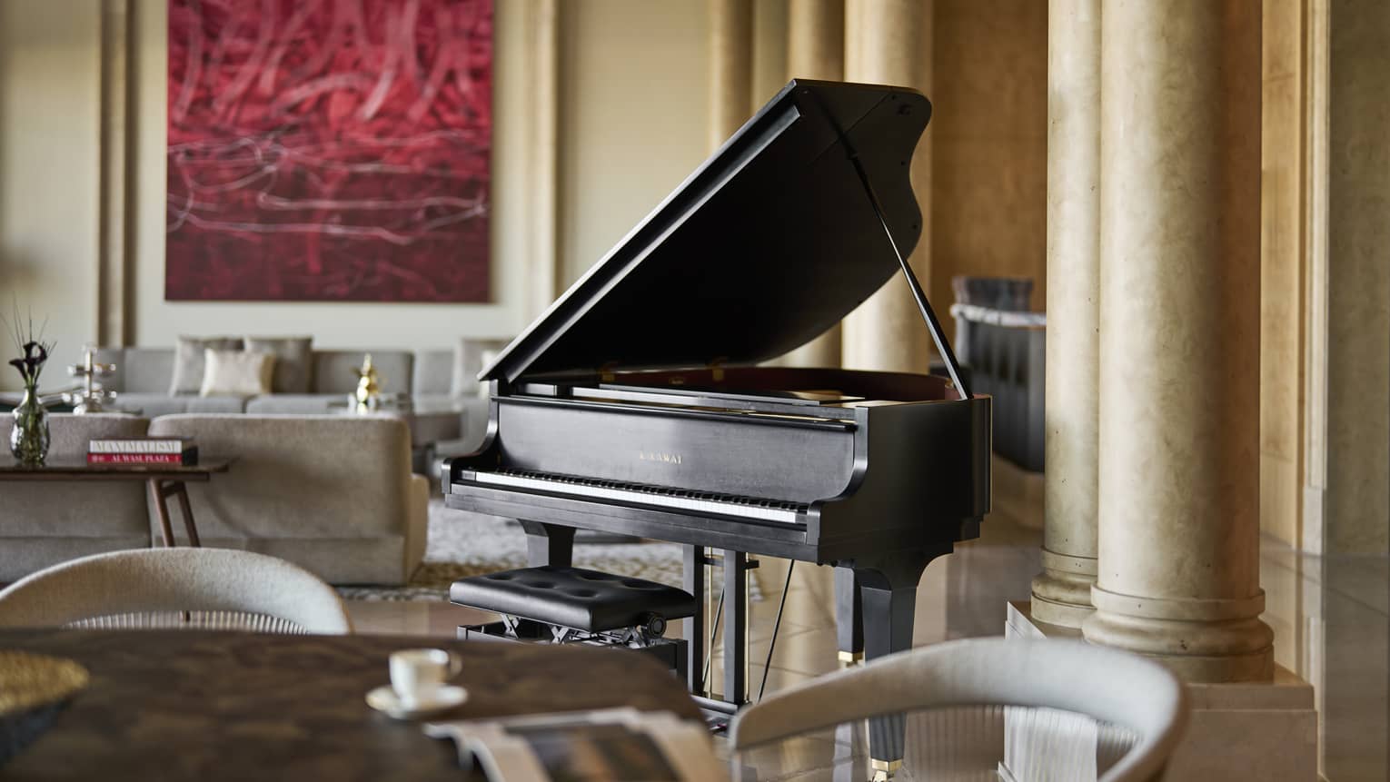 Black baby grand piano sits in the middle of a large hotel suite's living room