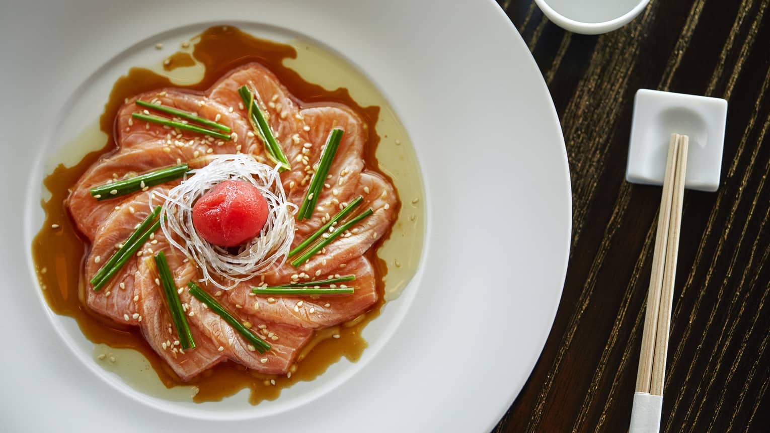 Aerial view of sashimi arranged as flower in dish, sauce and garnish