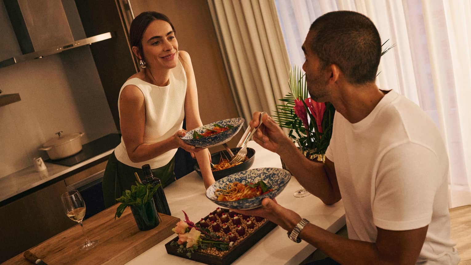 A couple sits at a kitchen island sharing food