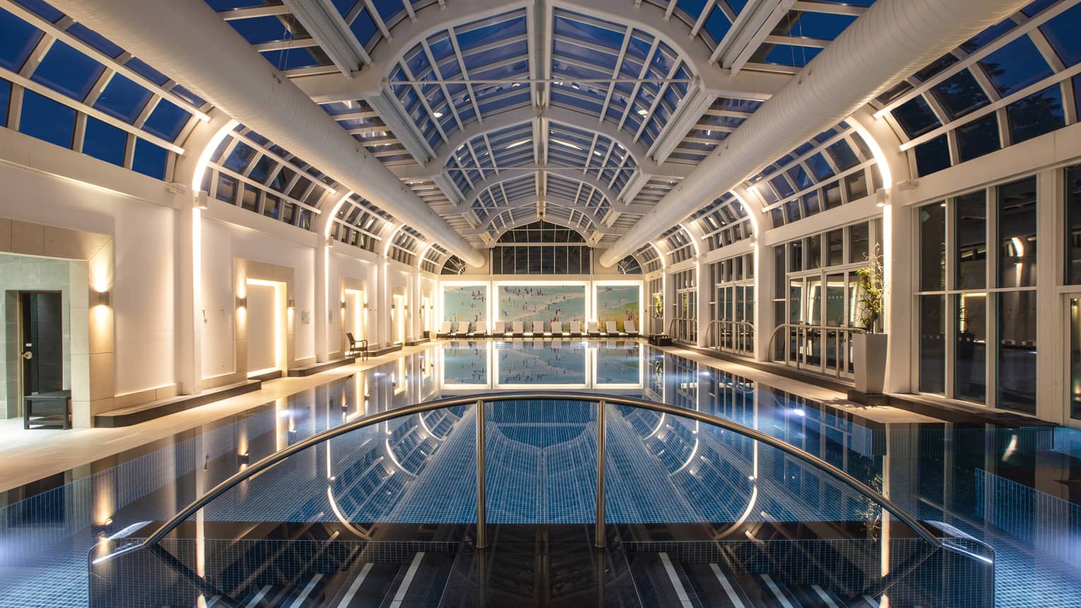 Deep blue indoor spa pool illuminated under skylight night view