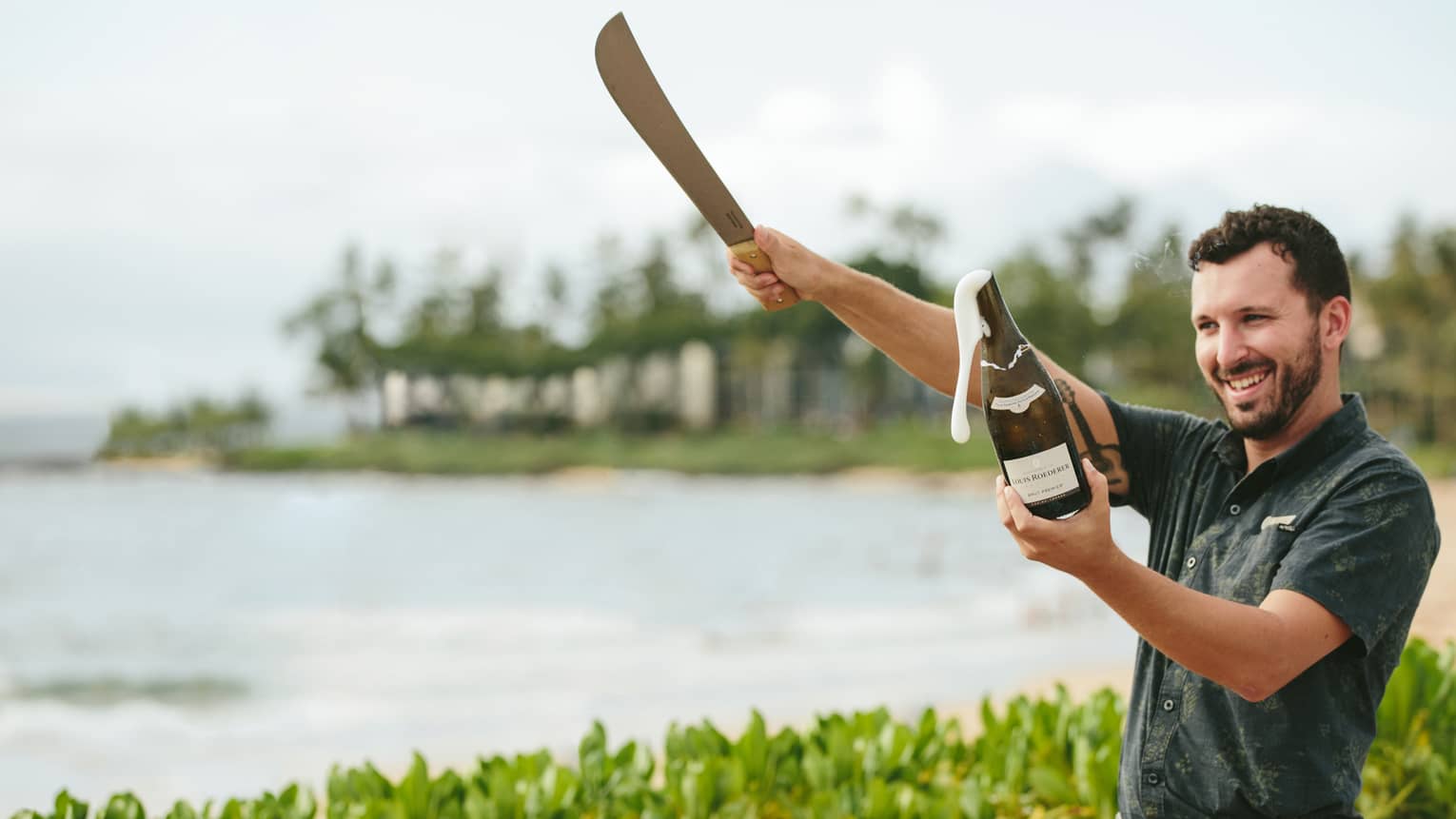 Man sabers a Champagne bottle on a tropical beach