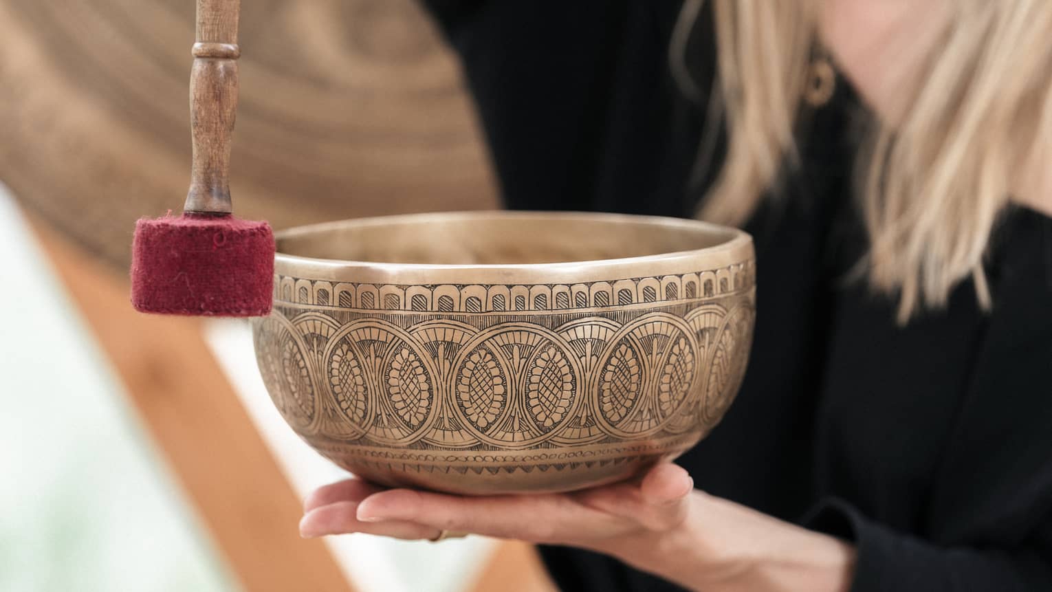 Person holding a gold engraved sound bath healing bowl