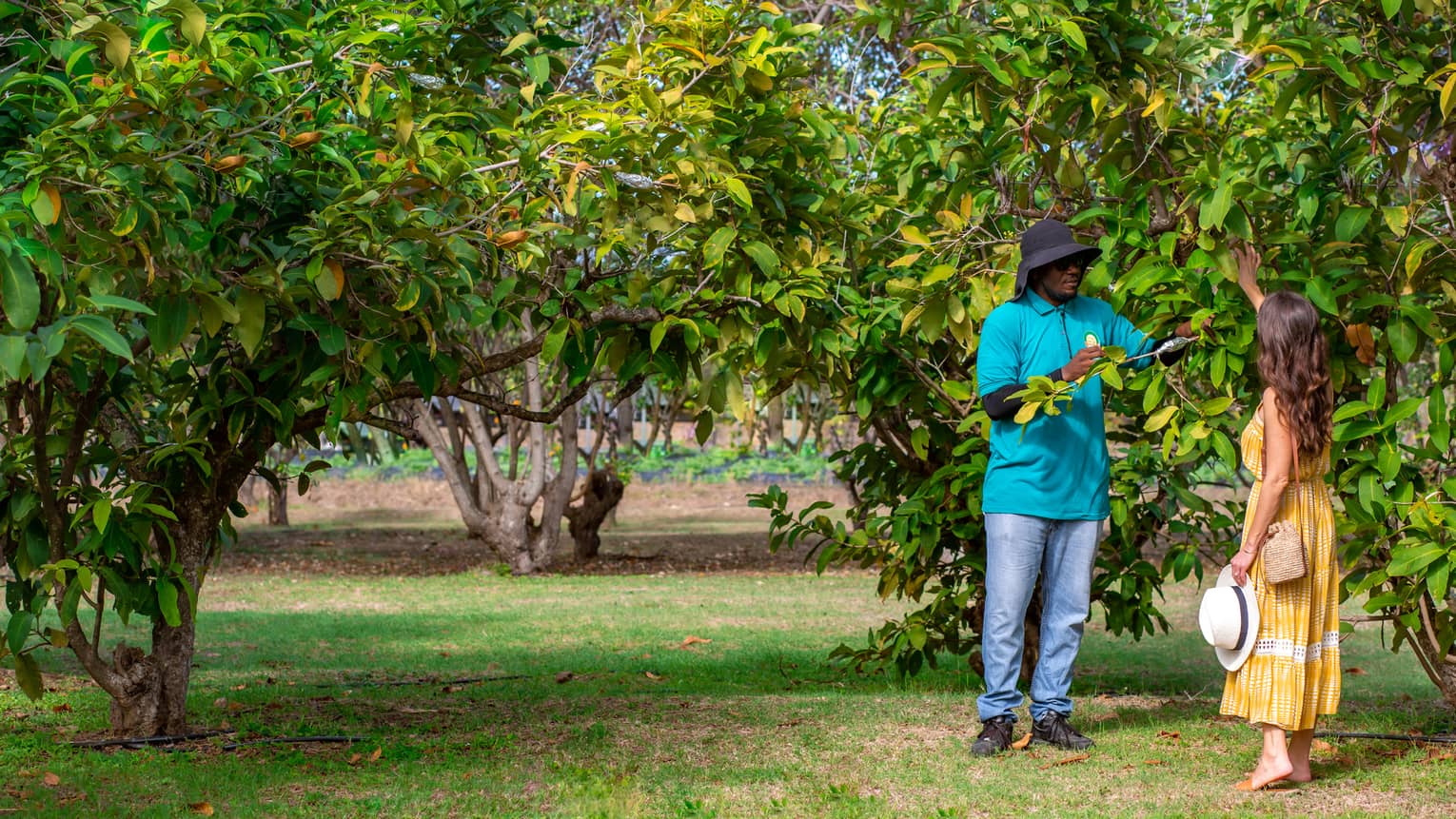 A man and woman near trees outside.
