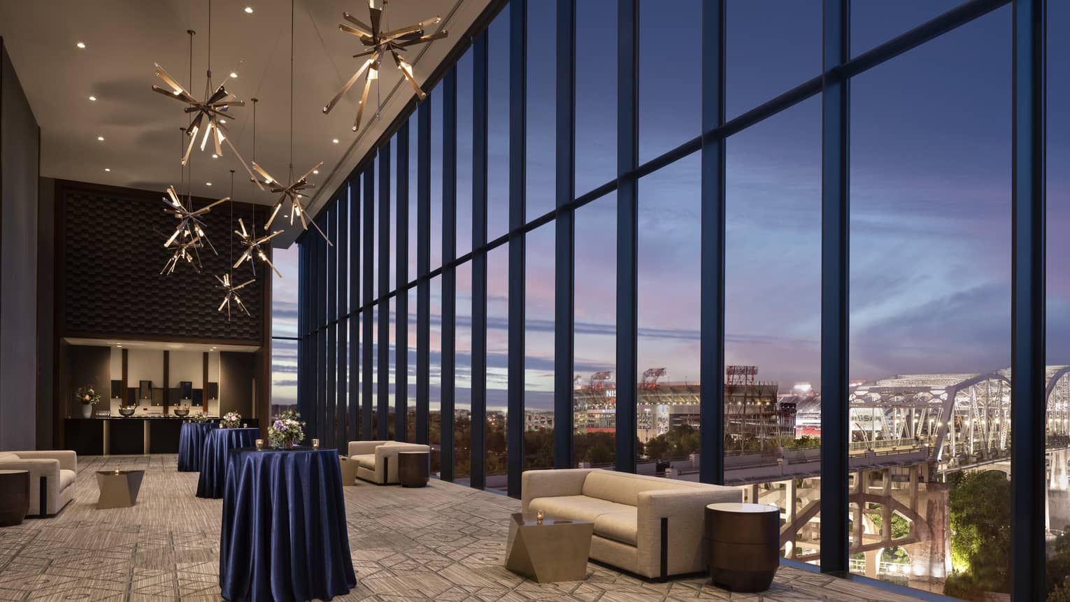 Indoor pre-function space with a wall of windows looking out to Nashville at dusk