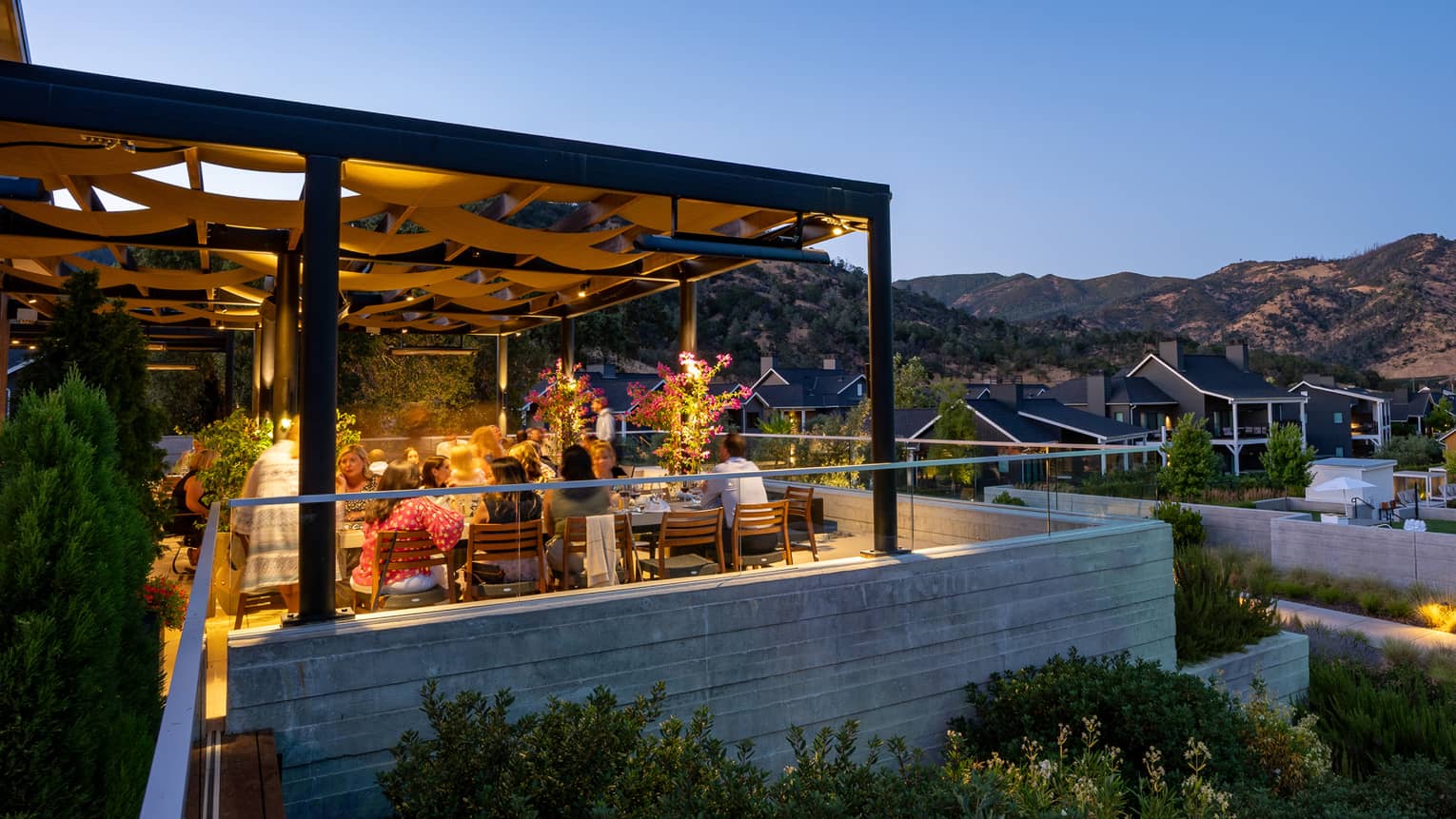 A patio with views of the mountains and dining tables with lighting above