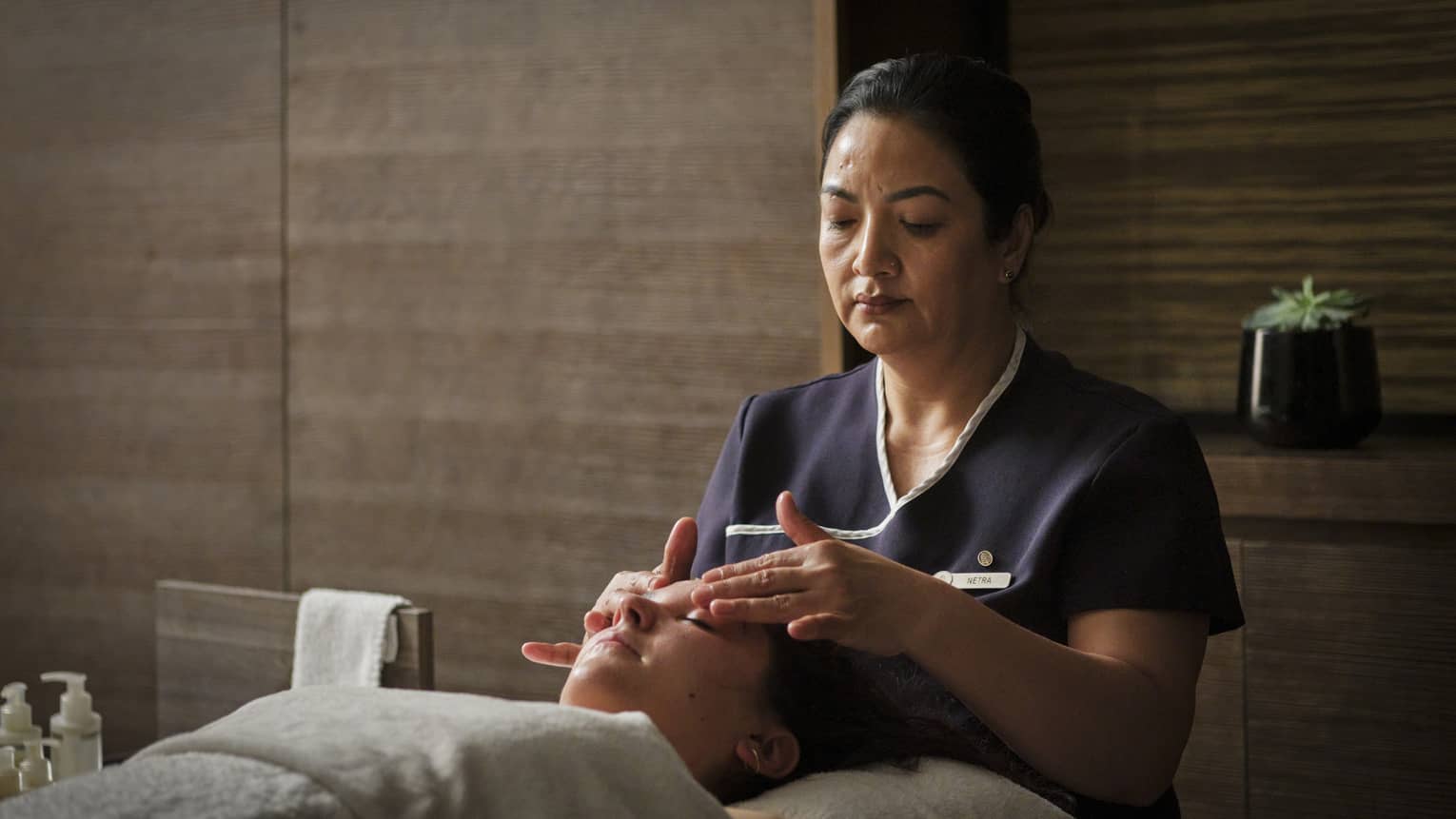 A spa team member giving a facial massage to a guest.