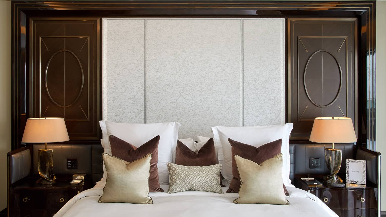 Luxury hotel bedroom king bed with gold and brown throw pillows and two nightstands