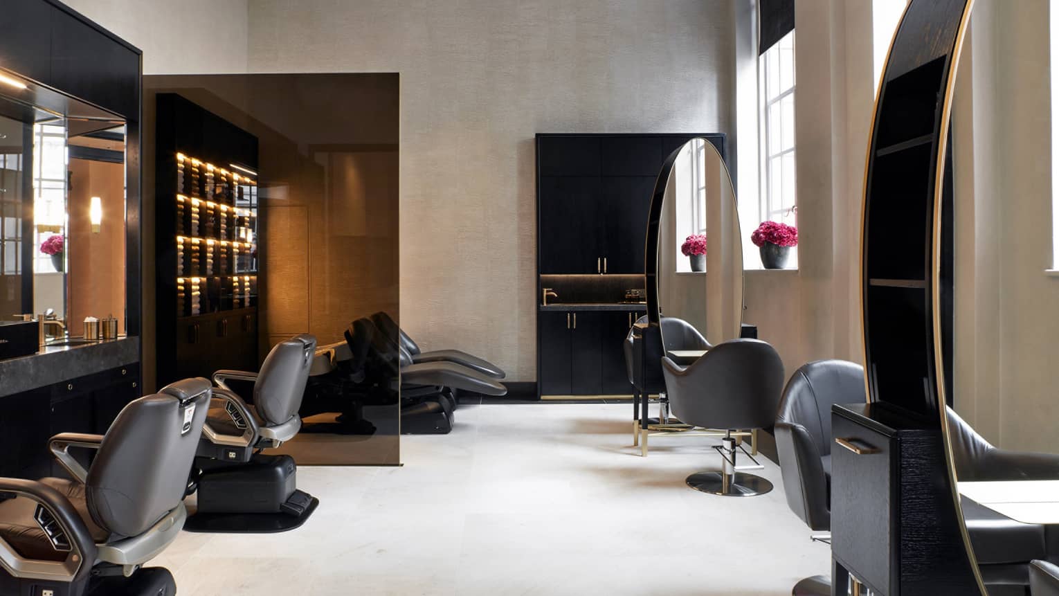 A spacious salon space with soft natural light from large windows, and decor in serene neutral hues