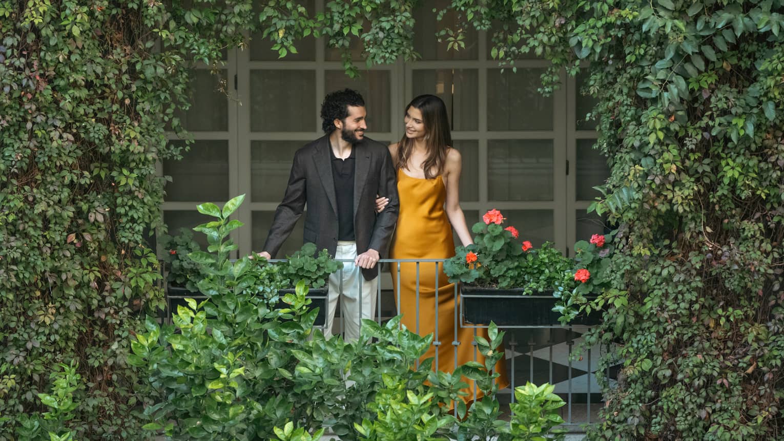 Two guests look out upon a greenery-filled outdoor space.