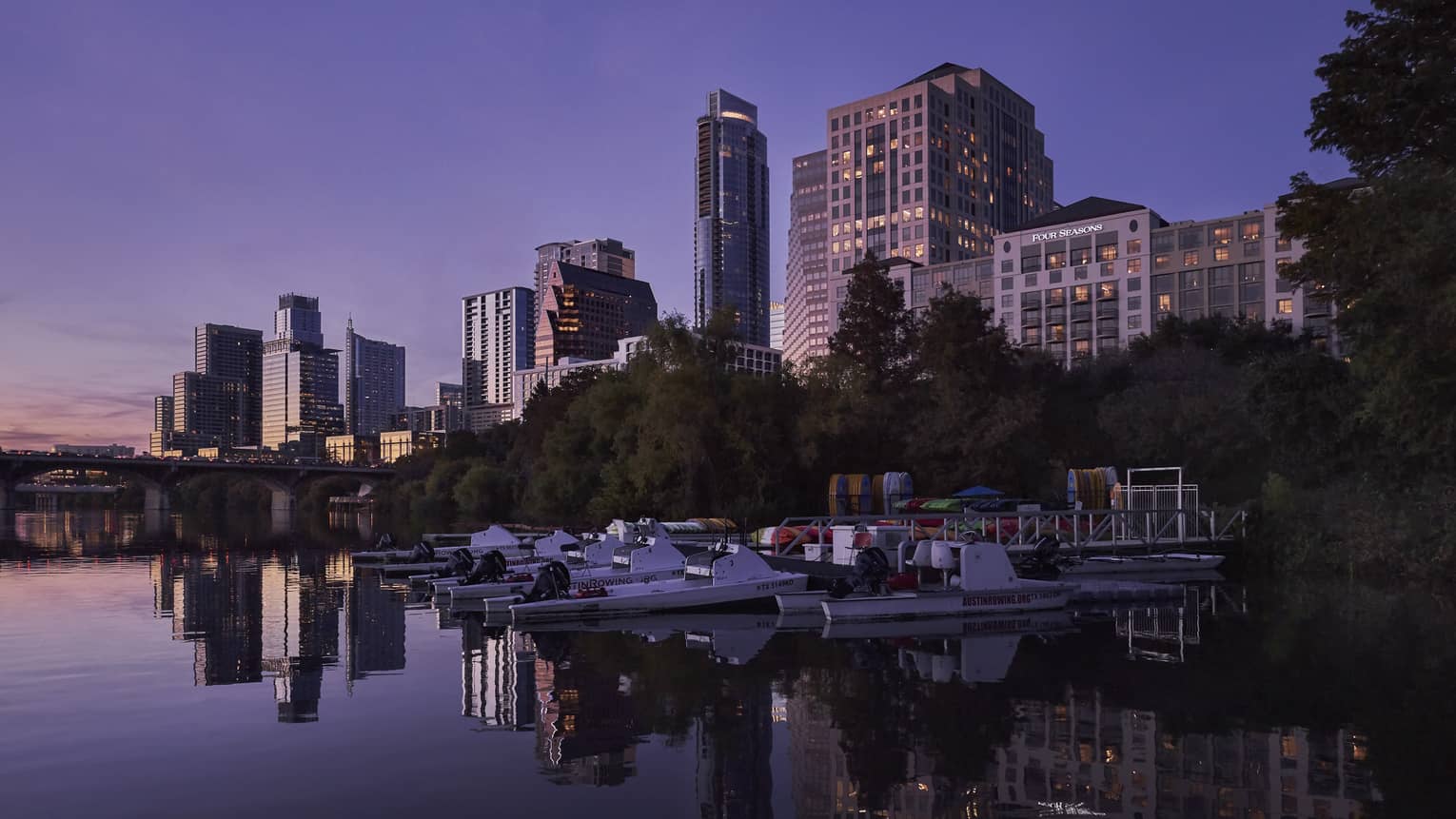 View of Austin city skyline, boats from Lady Bird Lake at dusk