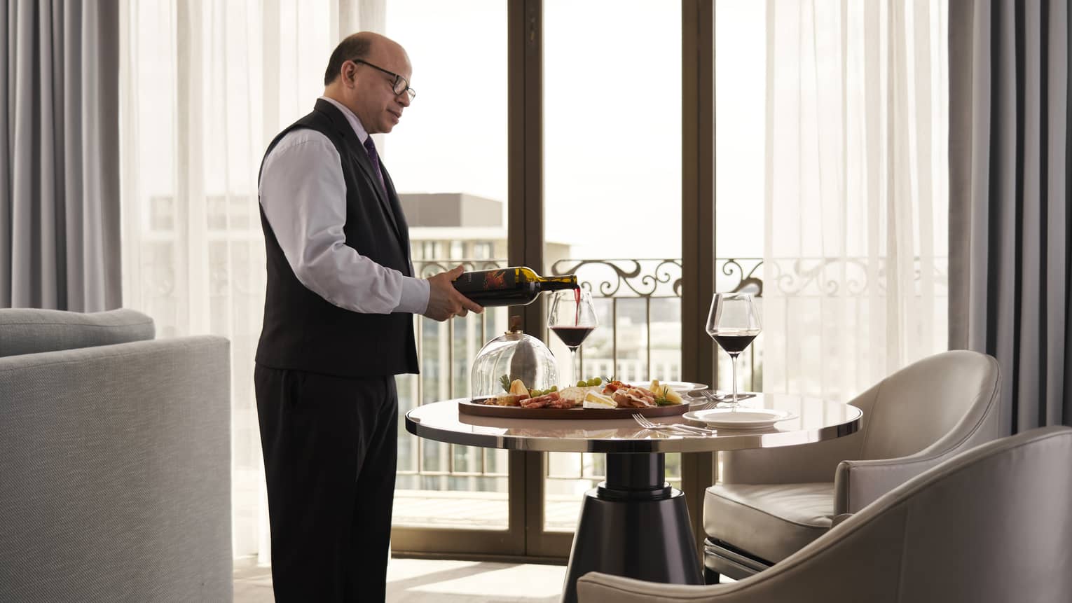 A team member pouring wine in a hotel room.