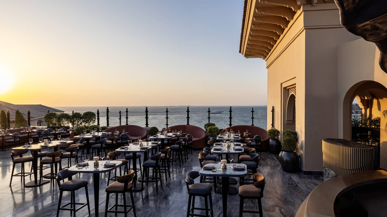 Rooftop bar of Dubai hotel during the day, with many tables and chairs and sea view