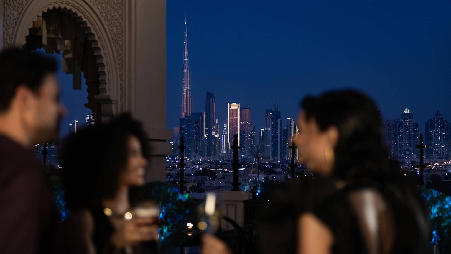 Friends mingle at a Dubai hotel rooftop bar with Dubai skyline view