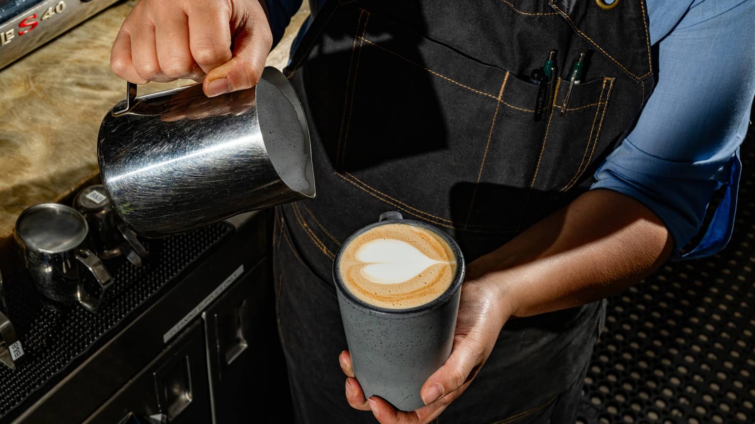 A person pouring milk in a mug of coffee