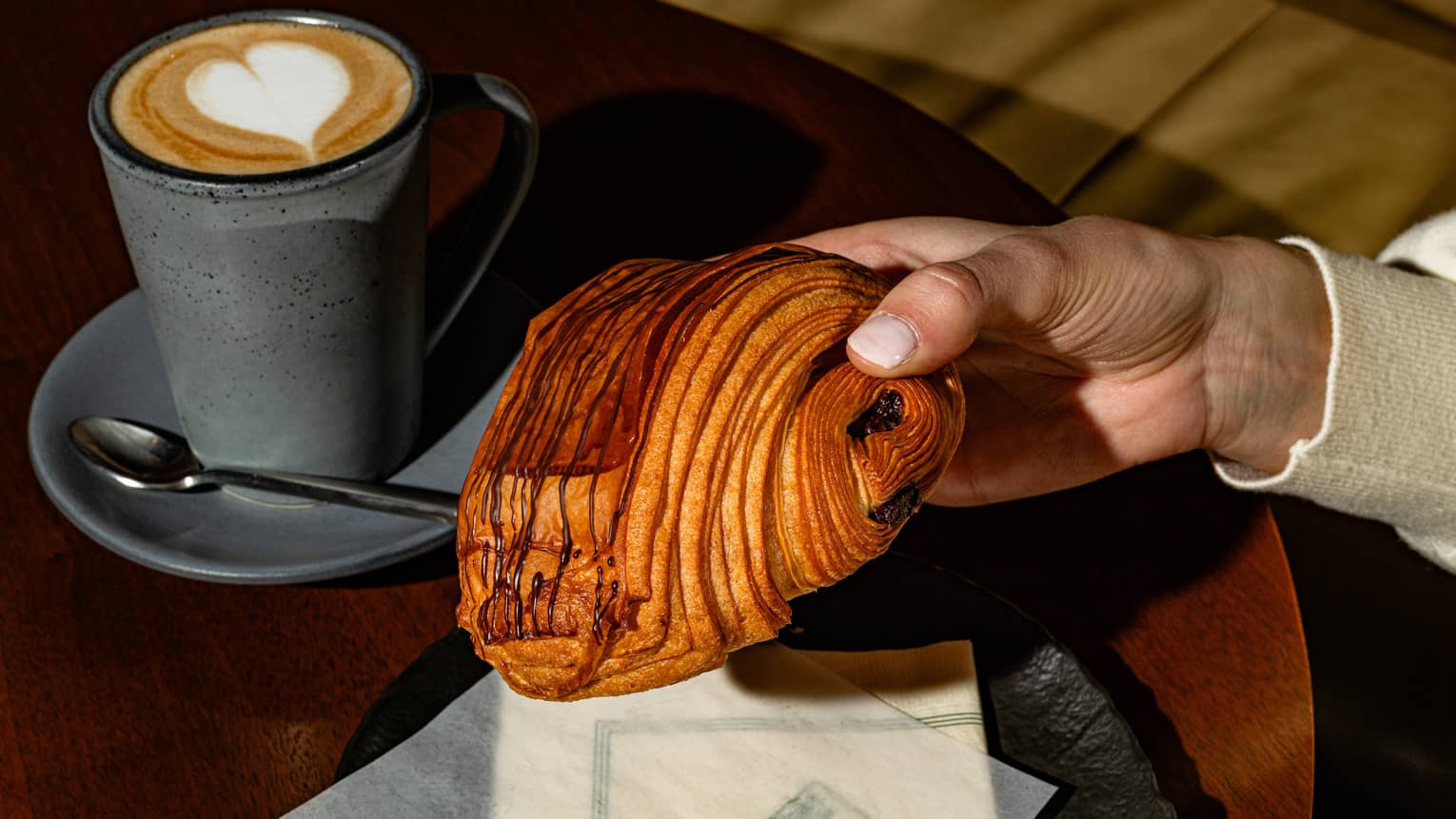A croissant with a mug of coffee and a spoon