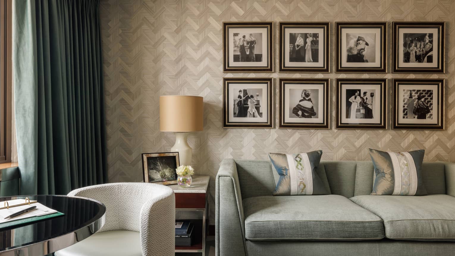 Luxury hotel suite with light blue sofa, round table and chair and four square framed photos on the wall at Four Seasons Hotel London at Park Lane