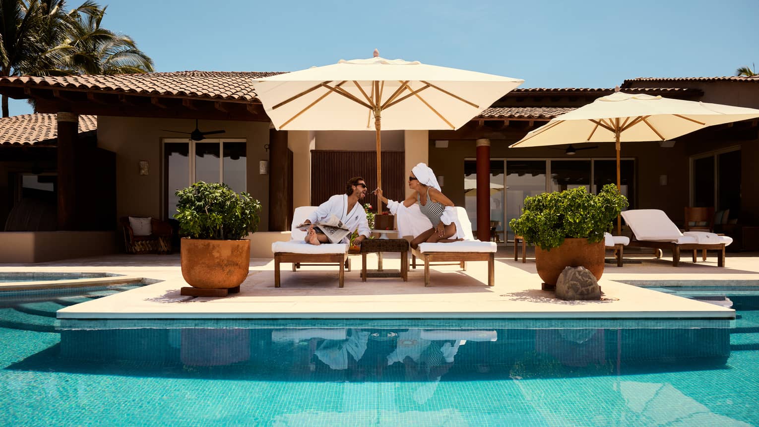 Man and woman relaxing on deck chairs next to the pool