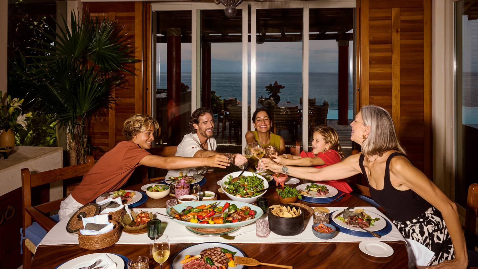 Family of five toasting at a table full of colourful dishes