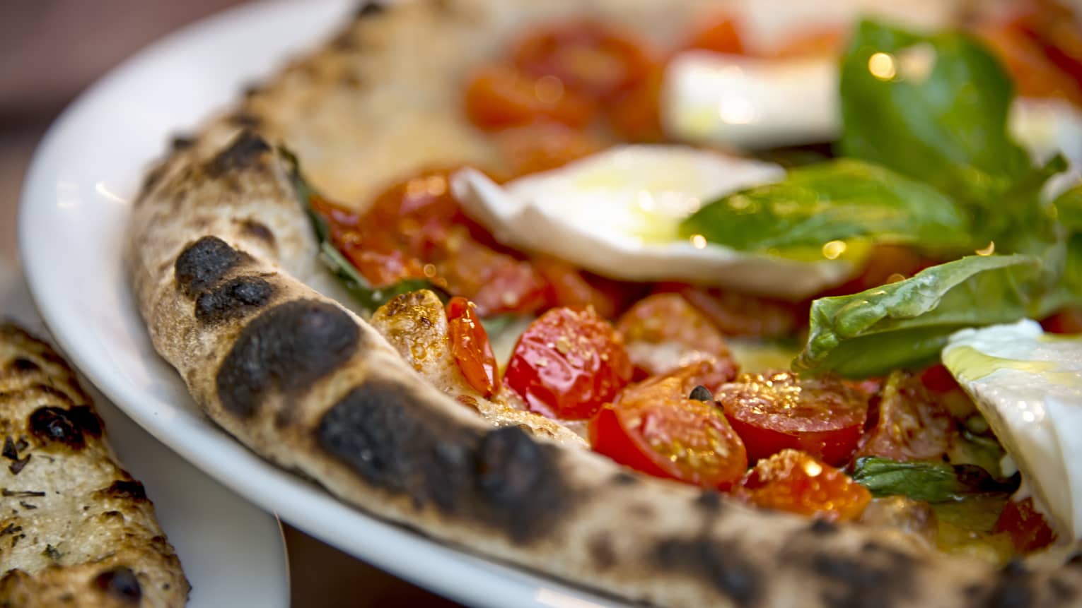 Close-up of Al Fresco signature pizza thin wheat crust, fresh cherry tomatoes, basil