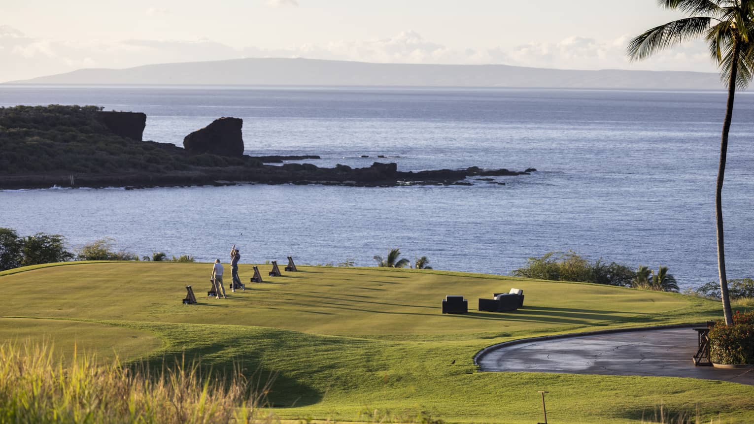 Golfers practicing on ocean-side golf course in Lanai, Hawaii
