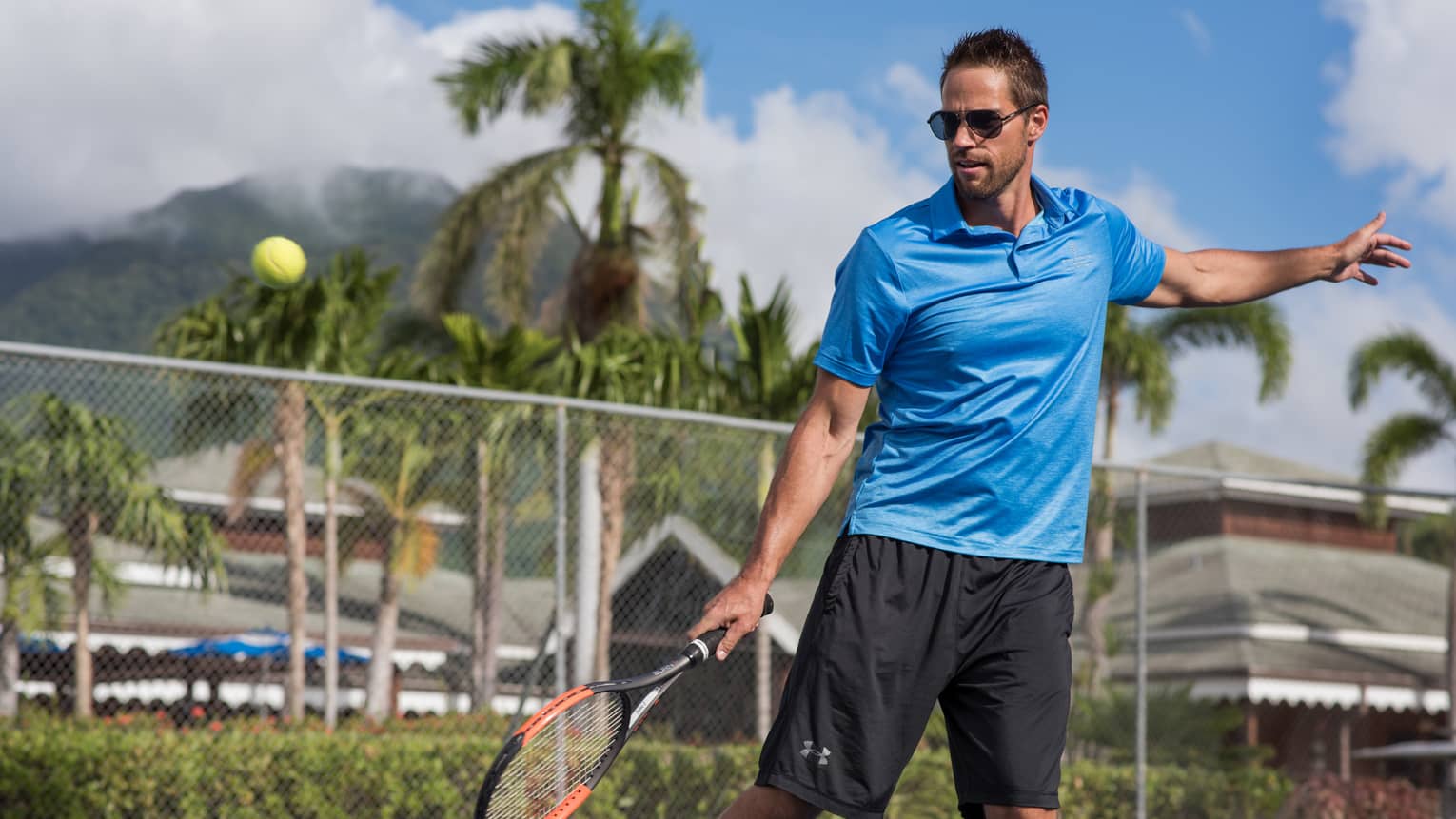 Tennis ball in air, man swings racket on court