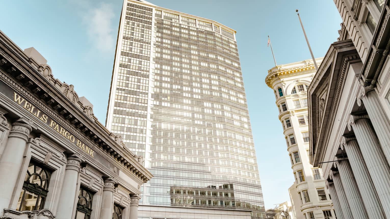 A large steel building surrounded by older stone buildings.