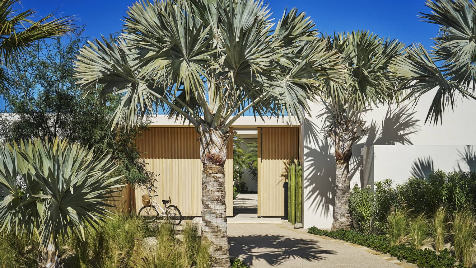 Entrance to private villa with large wooden gate and palm trees at Four Seasons Resort and Residences Los Cabos