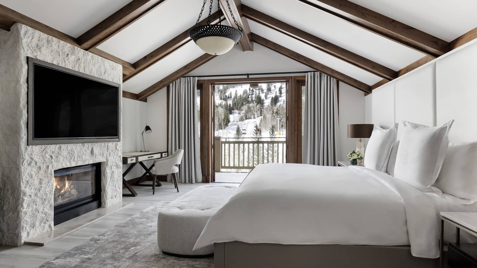 Bedroom with king bed, fireplace and TV, vaulted ceiling and mountain-view balcony