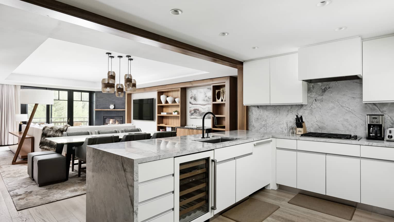 Modern kitchen with white cabinetry opening up to a mountain chic living room