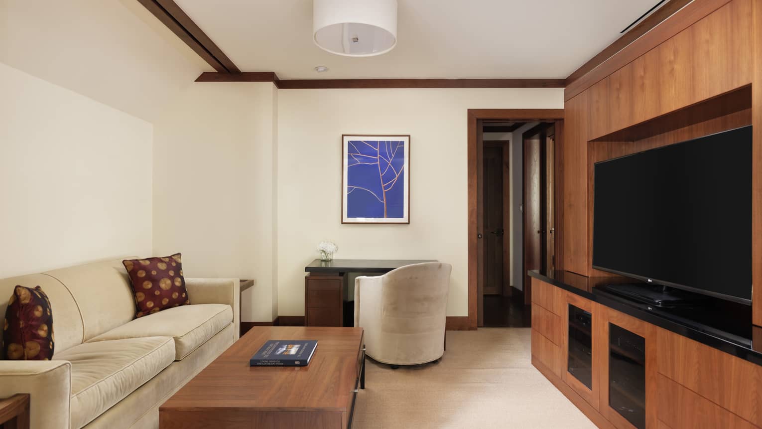 Media room with wooden entertainment center, TV, cream sofa, coffee table