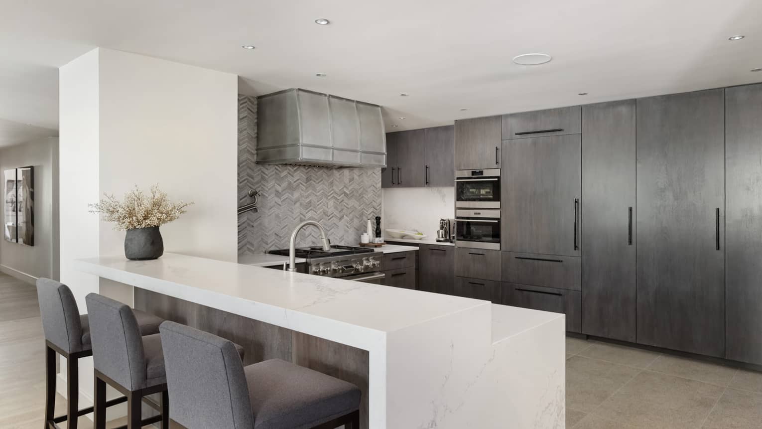 Modern kitchen with grey cabinetry, white marble counter with three grey counter stools, Lover's Leap at Four Seasons Resort and Residences Vail