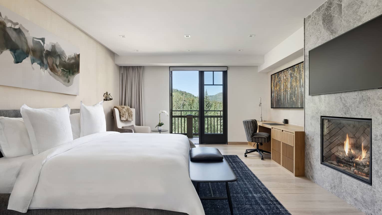Sleek bedroom with king bed, built-in fireplace and balcony at Four Seasons Vail
