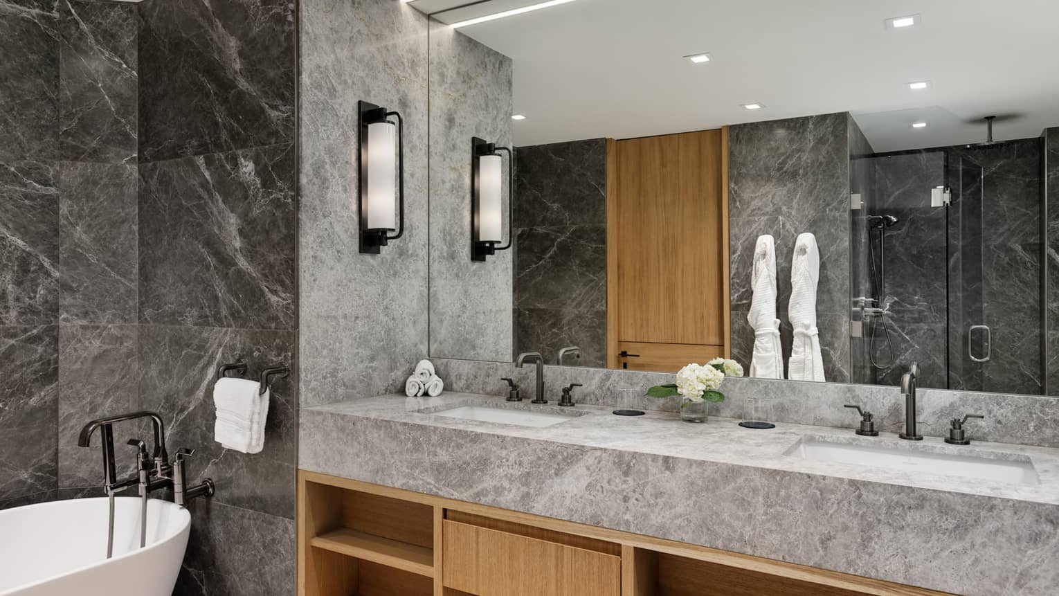 Sleek marble and stone bathroom with double vanity and free-standing tub