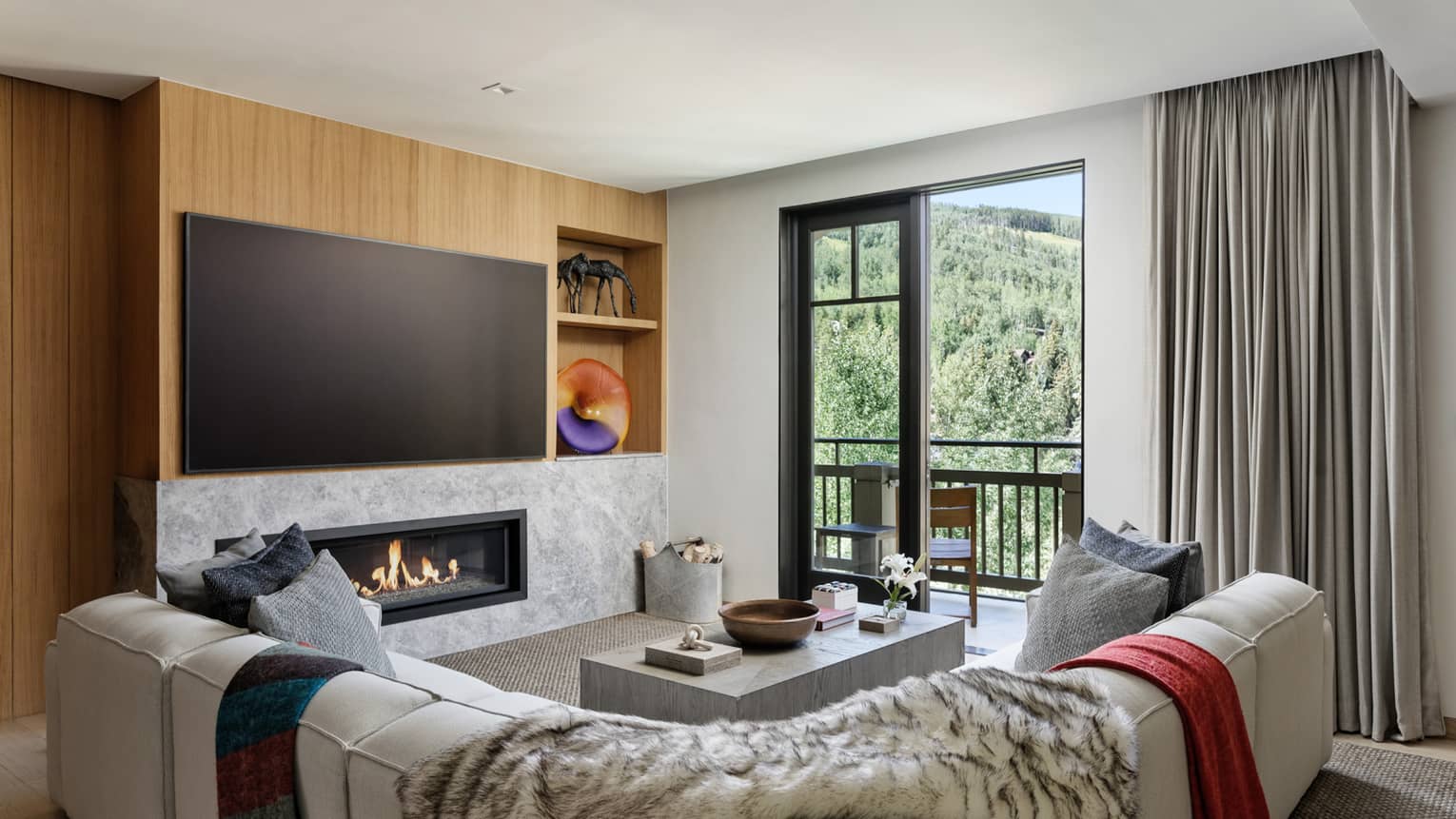 Living room with white sectional sofa, large TV, built-in fireplace and walk-out balcony at Four Seasons Residences Vail