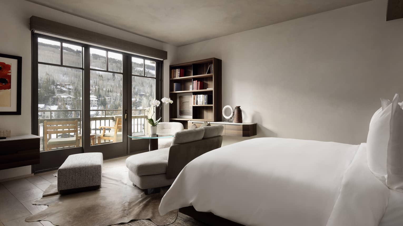 Bedroom with king bed and small sofa facing a walk-out terrace